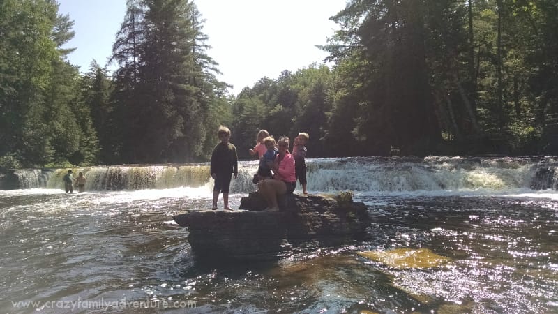 Posing for a picture on a rock in the middle of the river by the falls.