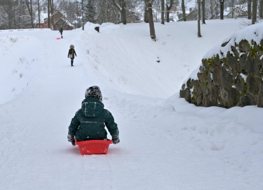 A kid going down a hill on a sled, sledding hills in Wisconsin