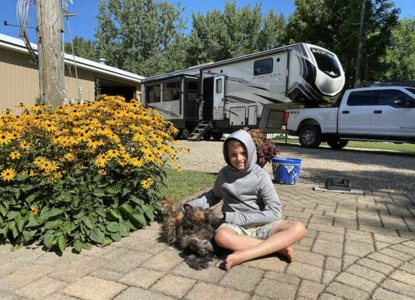 Shows a kid petting a dog in front of an RV, Boondocks Welcome