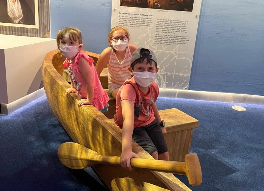 Shows a Wooden Boat and oar with kids in it at the museum Gateway Arch National Park
