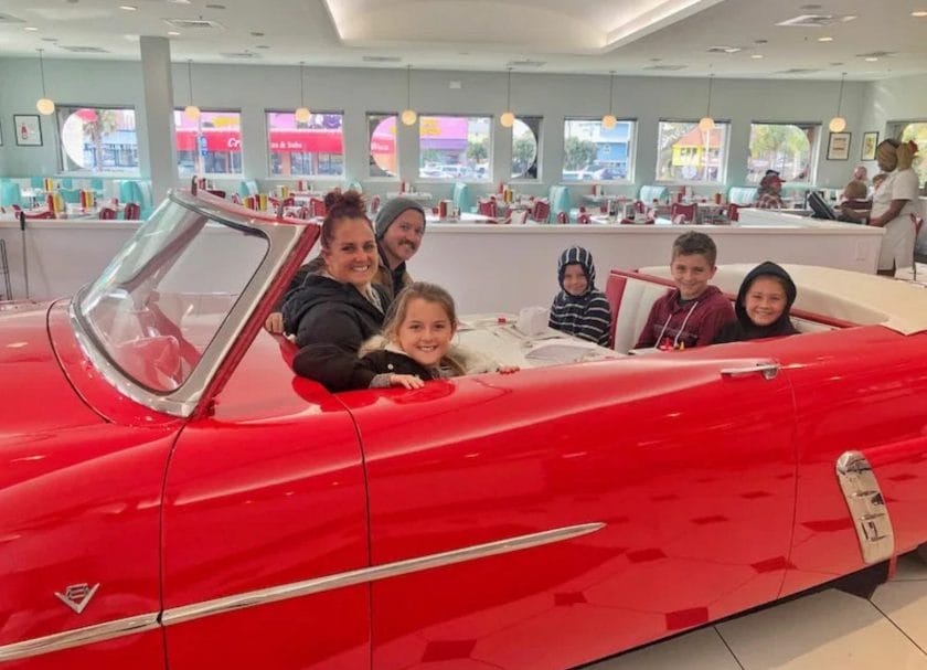 Family sitting in a classic car that has been converted into a booth for dining