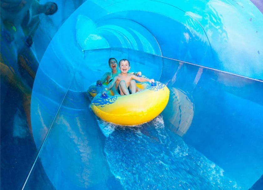 Shows a mother and son laughing coming down a water slide on an inner tube at Great Wolf Lodge, indoor water parks in Michigan