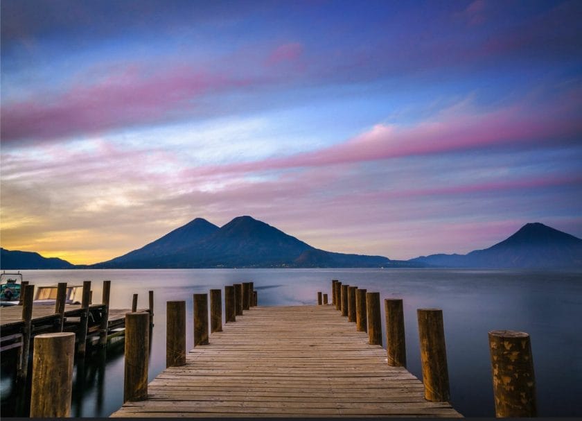 Picture of the sun setting behind a volcano from a pier overlooking Lake Atitlán, things to do in Guatemala