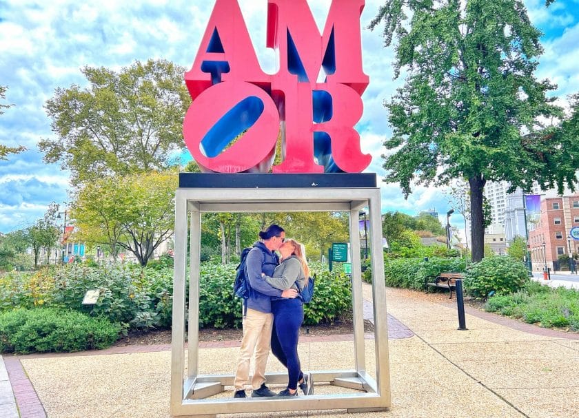 A couple kissing under the Amor Sign in Philadelphia.