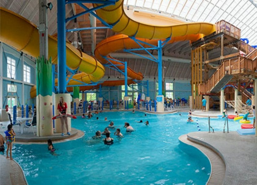 Shows families playing in a pool under a large overhead water slide at Breaker Bay Resort, indoor water parks Wisconsin