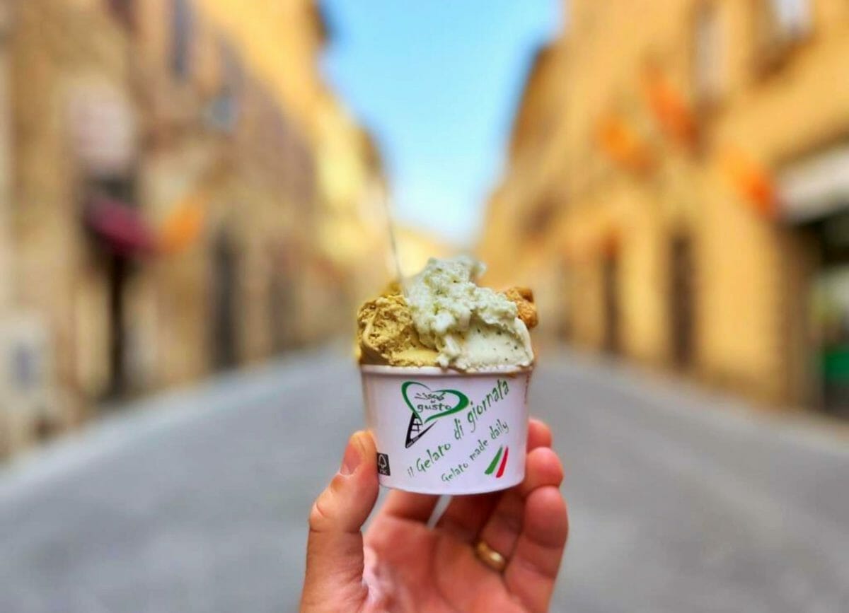 Shows a hand holding a cup of gelato at L'isola del Gusto Gelateria in Tuscany, Things to do in Tuscany
