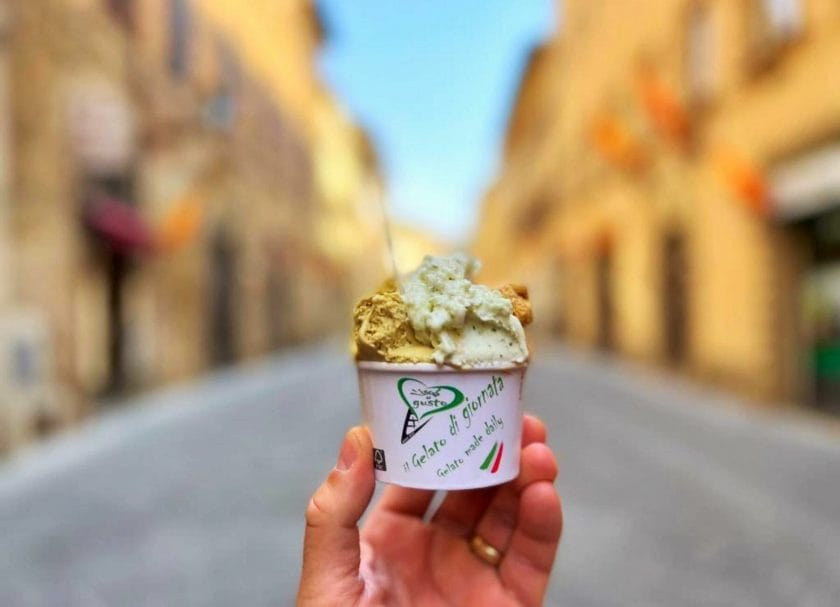 Shows a hand holding a cup of gelato at L'isola del Gusto Gelateria in Tuscany, Things to do in Tuscany