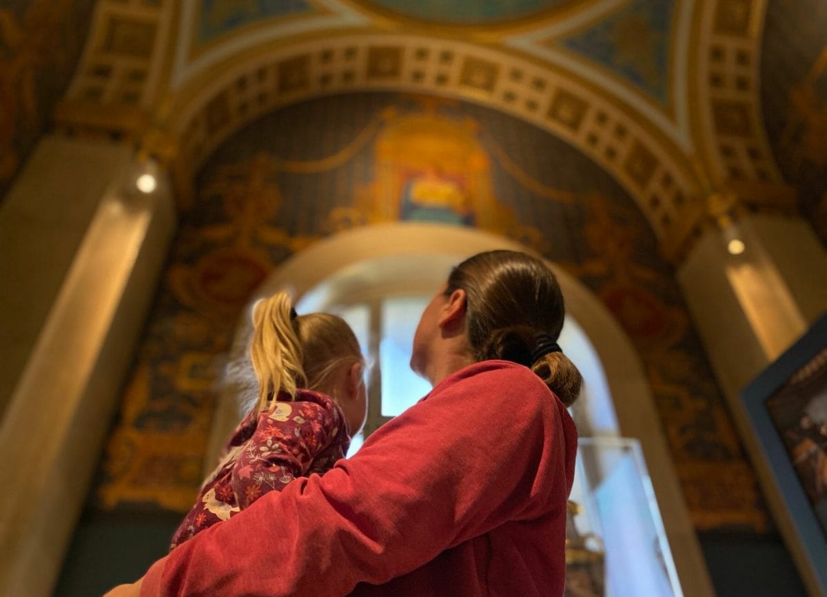 Shows a mother holding her daughter looking at the ceiling of the St Louis Art Museum, things to do in St Louis