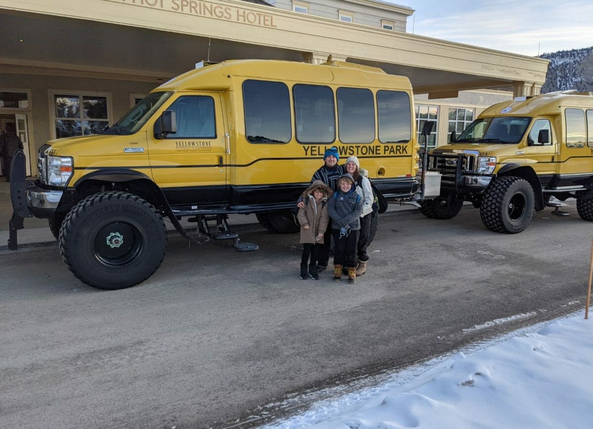 A family standing in front of a Yellowstone Park Snowcoach, Yellowstone in Winter