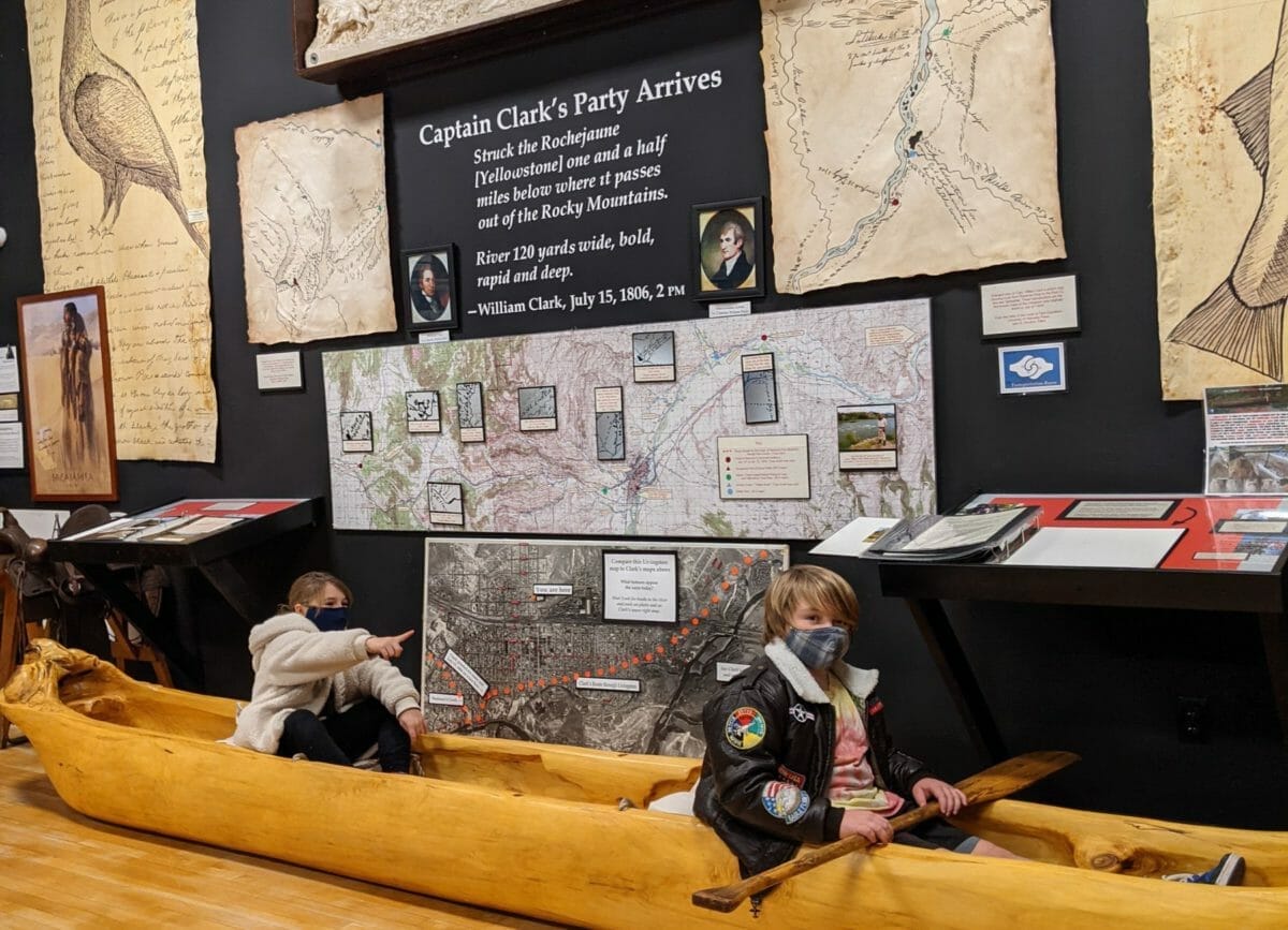 Shows kids in an ancient canoe in the Yellowstone Gateway Museum, Yellowstone in Winter