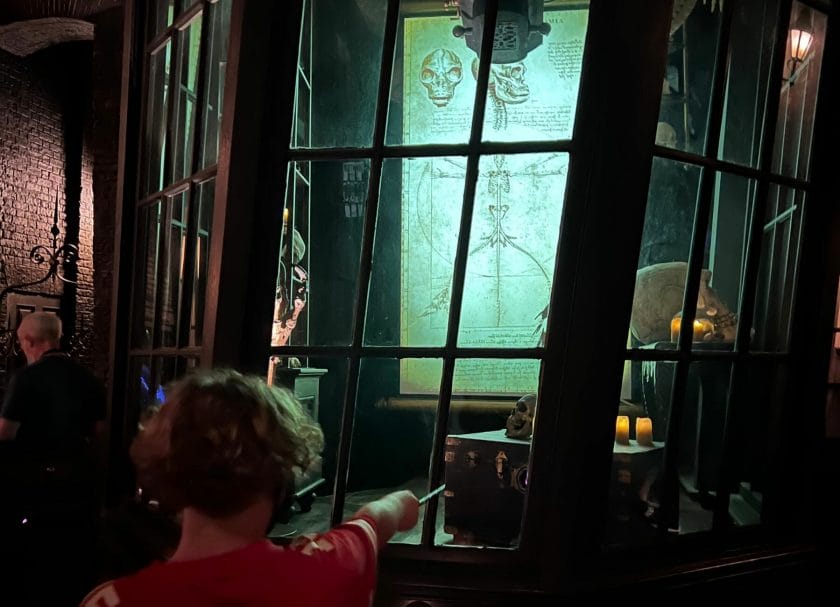Shows a little boy looking through a window at Borgin and Burkes in Knockturn Alley, Harry Potter World Rides