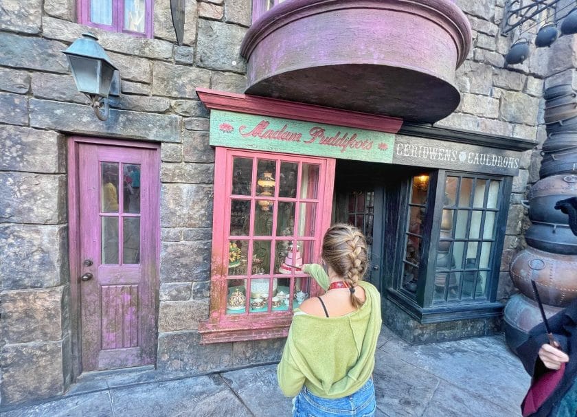 Shows a girl standing in front of Madam Puddifoots Sweet Shop, Harry Potter World Rides