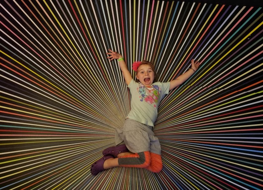 Shows a little girl laying on an interactive art display at Meow Wolf Santa Fe, Meow Wolf Review