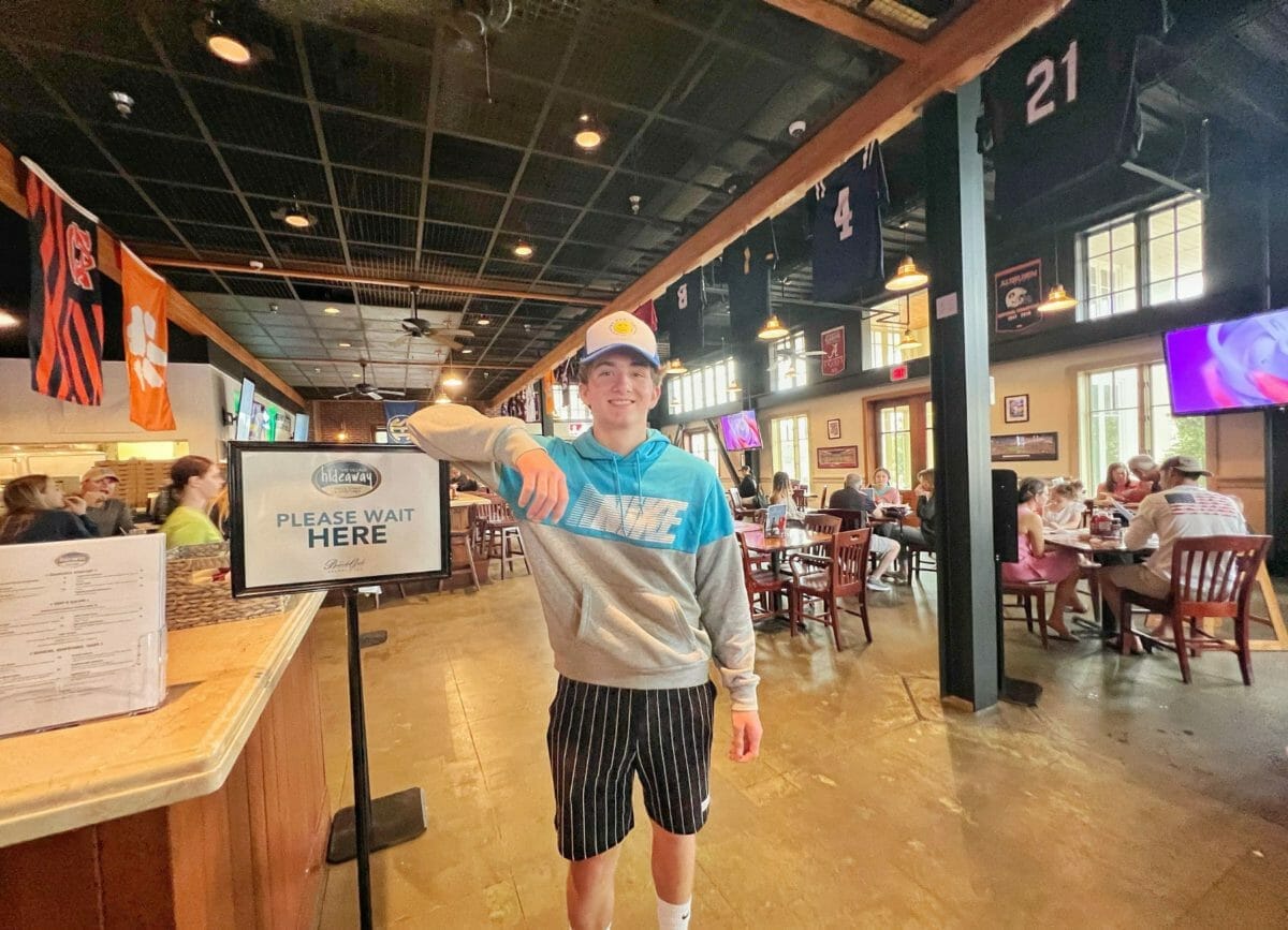 Carson standing by the sign at the Village Hideaway.