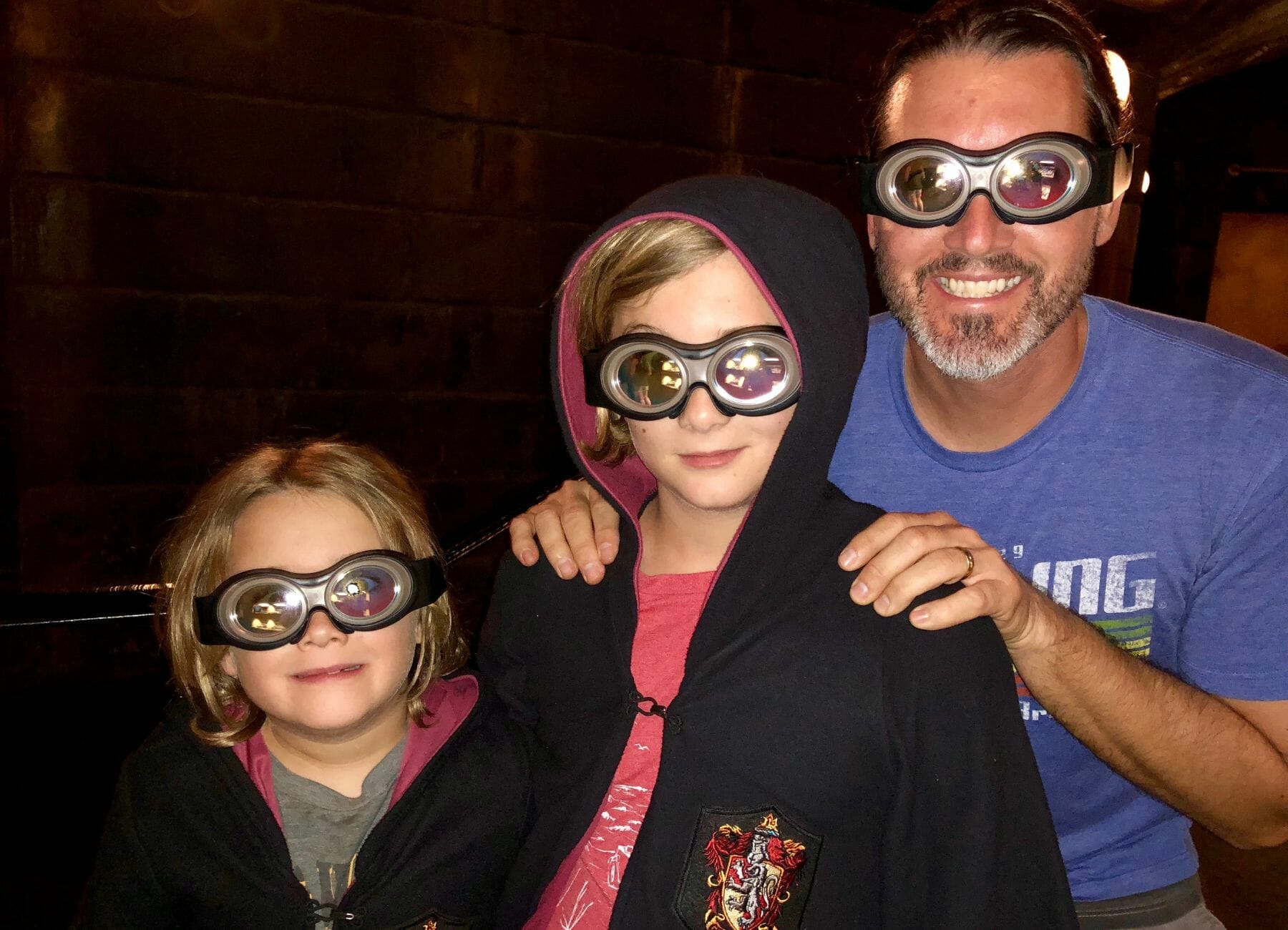 A dad and 2 kids wearing Minion Goggles, Universal vs Island of Adventure