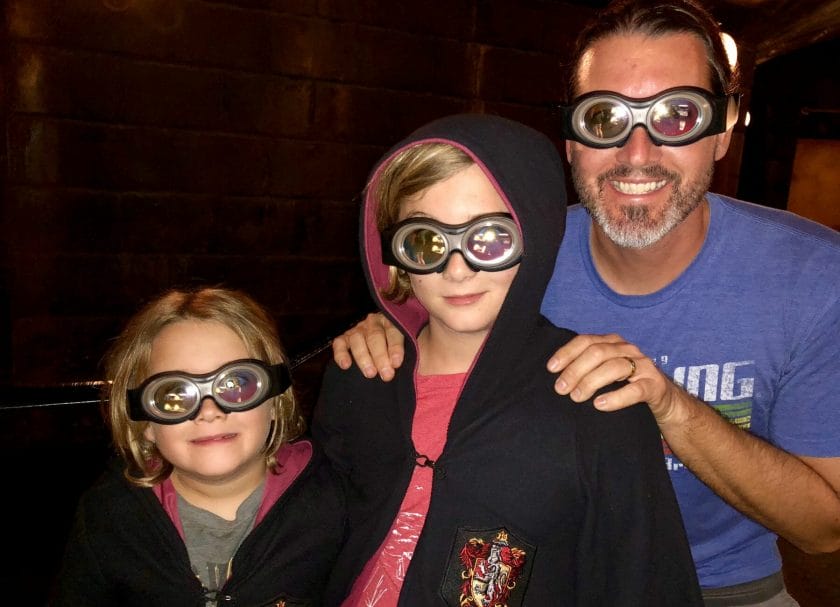 A dad and 2 kids wearing Minion Goggles, Universal vs Island of Adventure