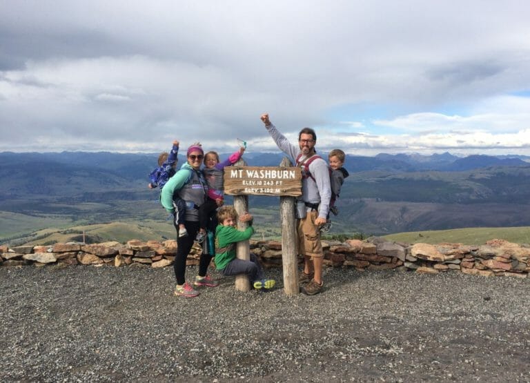 Our family standing by the sign at the top of Mount Washburn