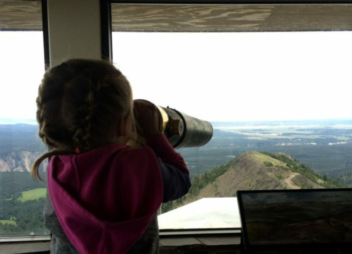 Melia looking through telescope on the Mount Washburn hike at the lookout tower.