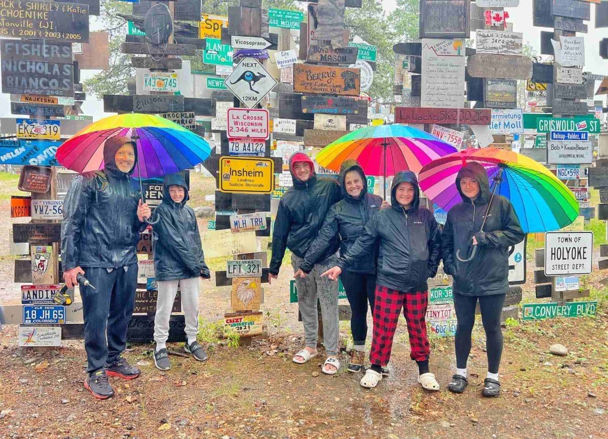 Family pointing at the sign we added to the Sign Post Forest on the Alaska Highway
