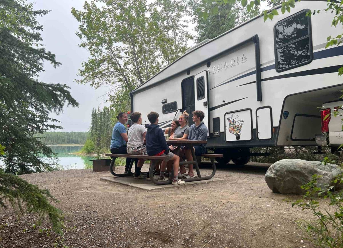 Family in front of an RV at the picnic table. 